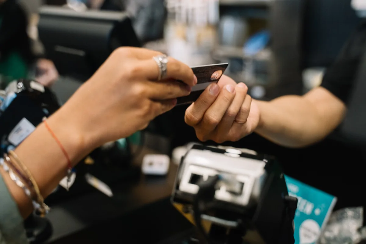 Close-up of hands completing a payment transaction at a retail checkout using a bank card