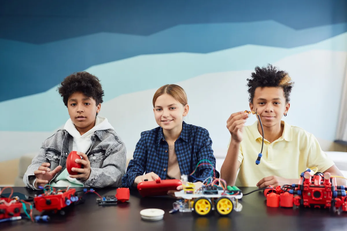 Three children working together on robotics project — matching STEM toys to child developmental stage