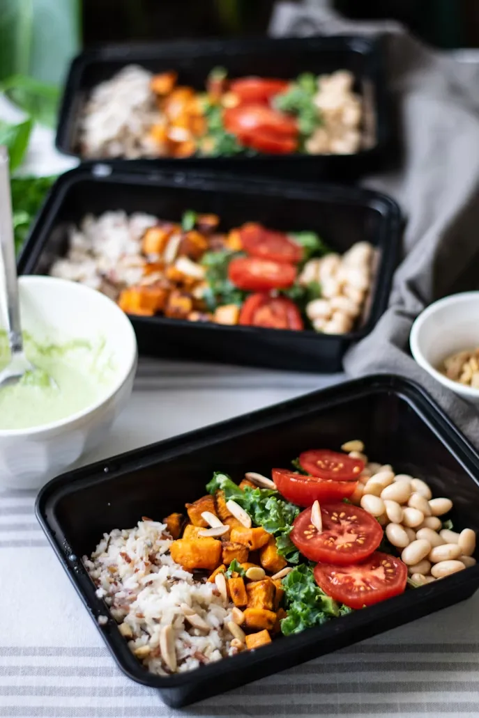 Two trays of healthy meal prep containers with balanced food portions