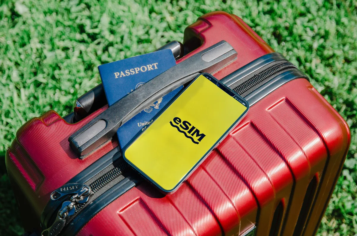 Red suitcase with smartphone showing eSIM app and passport