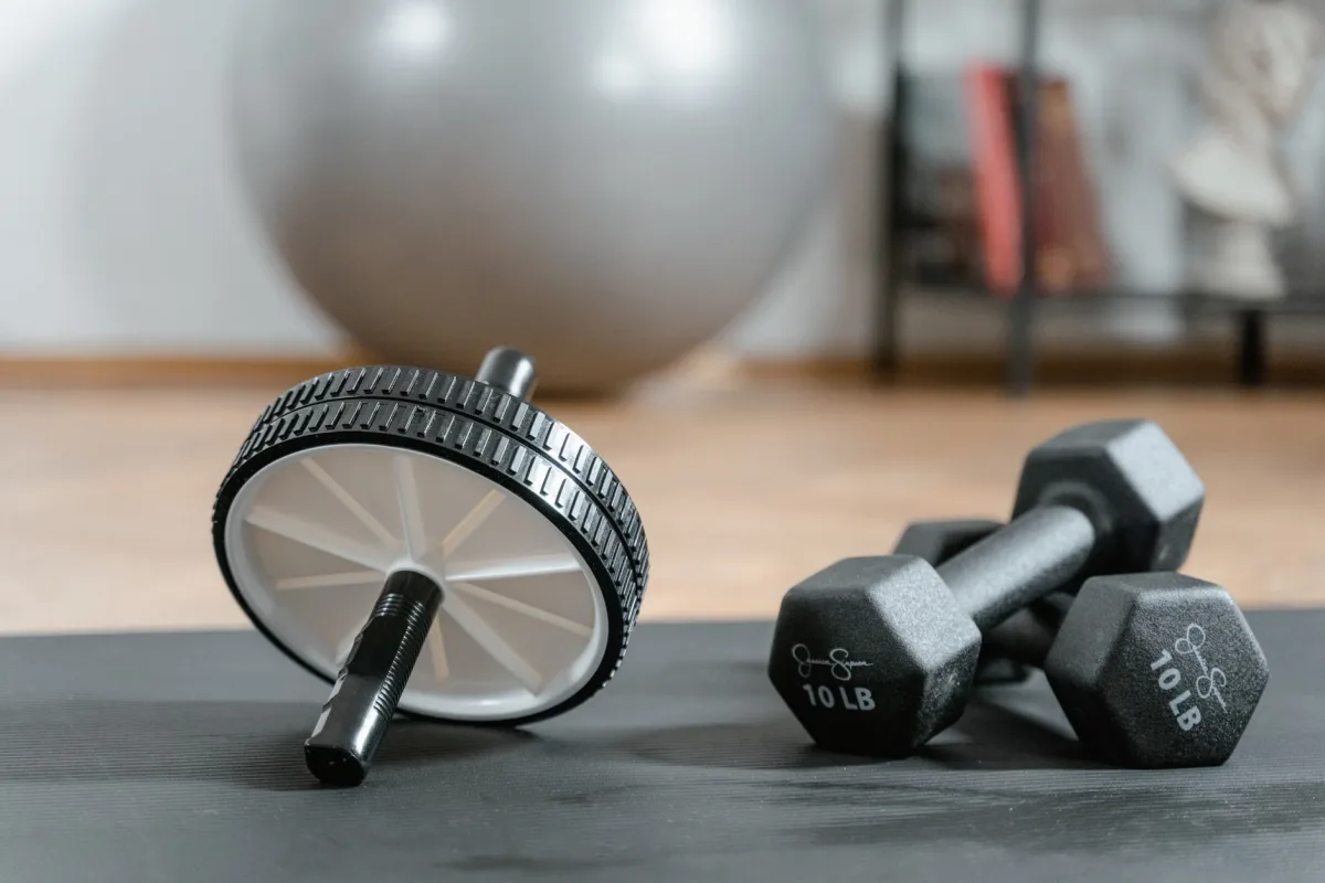 Ab wheel and dumbbells on mat in home gym setup