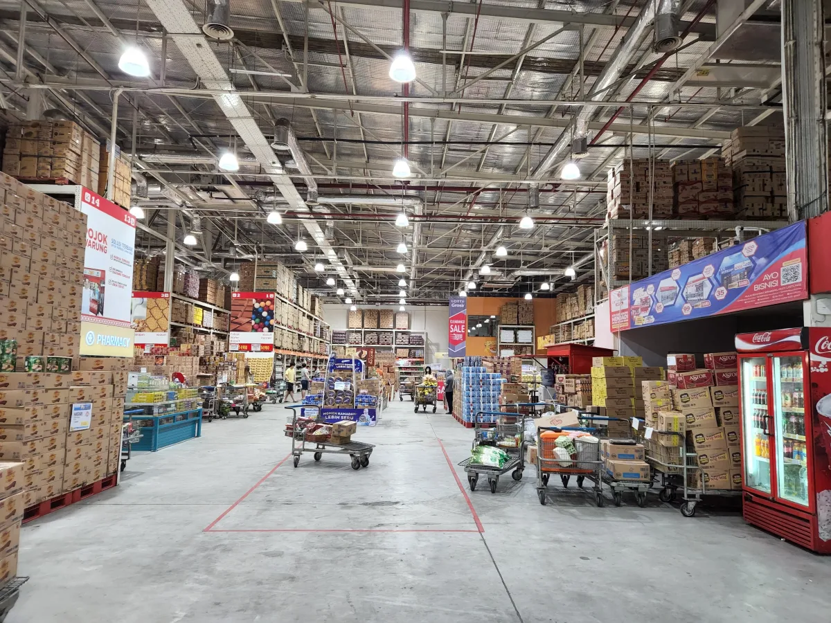 Warehouse store aisle with stacked bulk goods illuminated under bright industrial lighting
