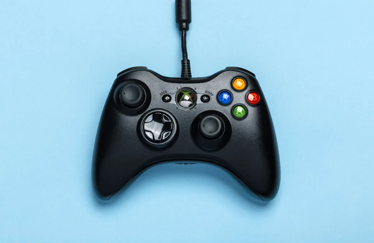 Black Xbox controller on blue background — Xbox keys work across console and PC via Xbox Live
