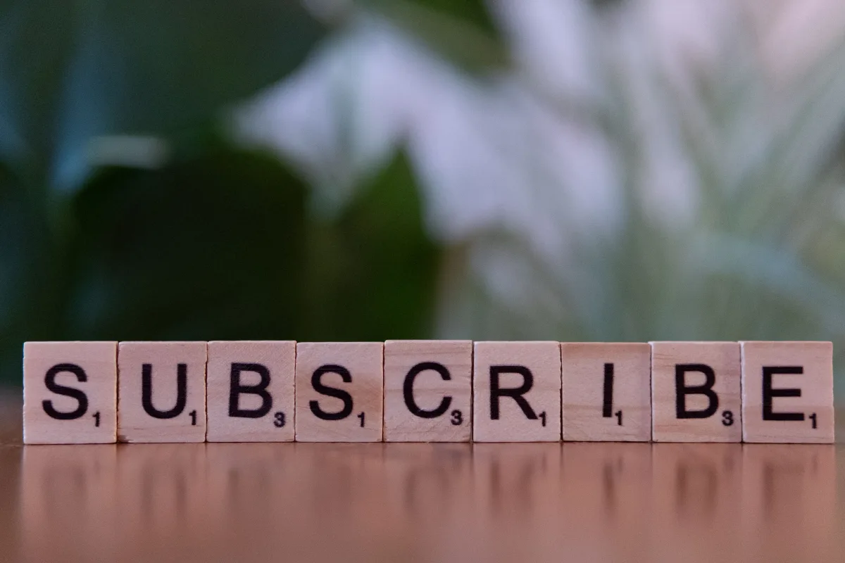 Close-up of the word SUBSCRIBE spelled with wooden letter tiles