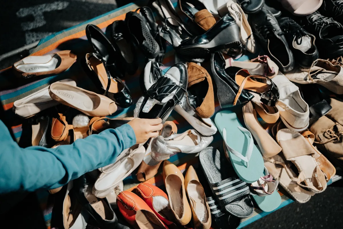 Hands selecting a shoe at an outdoor footwear market stall