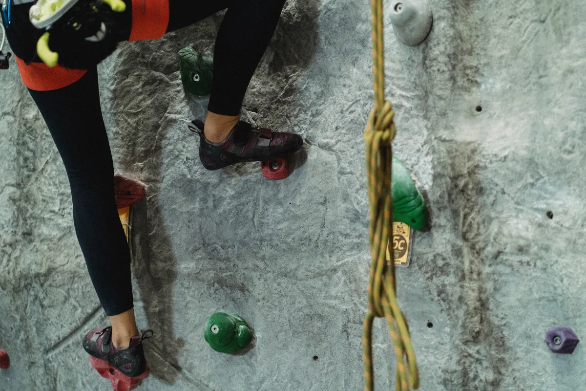 Climber in harness and belay gear on an outdoor rock face