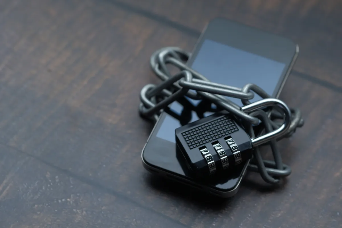 Close-up of a smartphone wrapped in a chain with a padlock symbolizing digital privacy