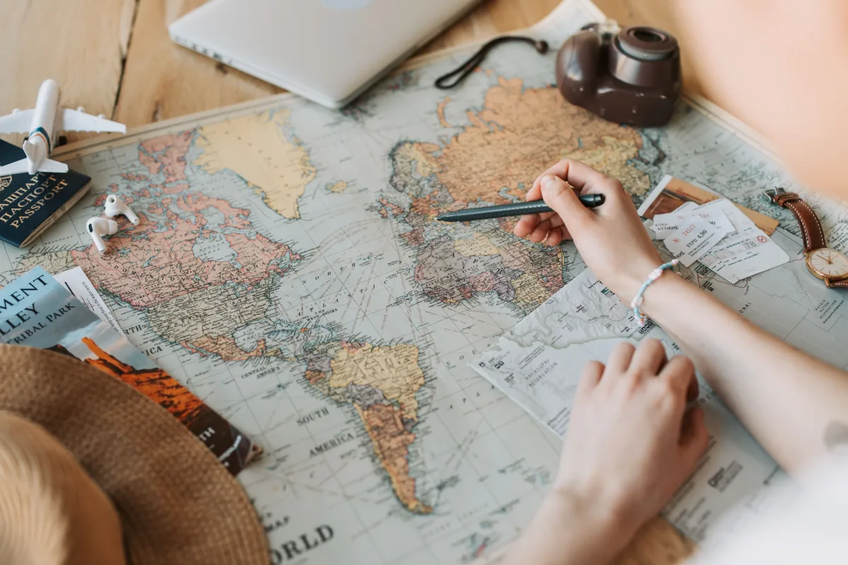 Traveler marking destinations on a map with passport and camera nearby