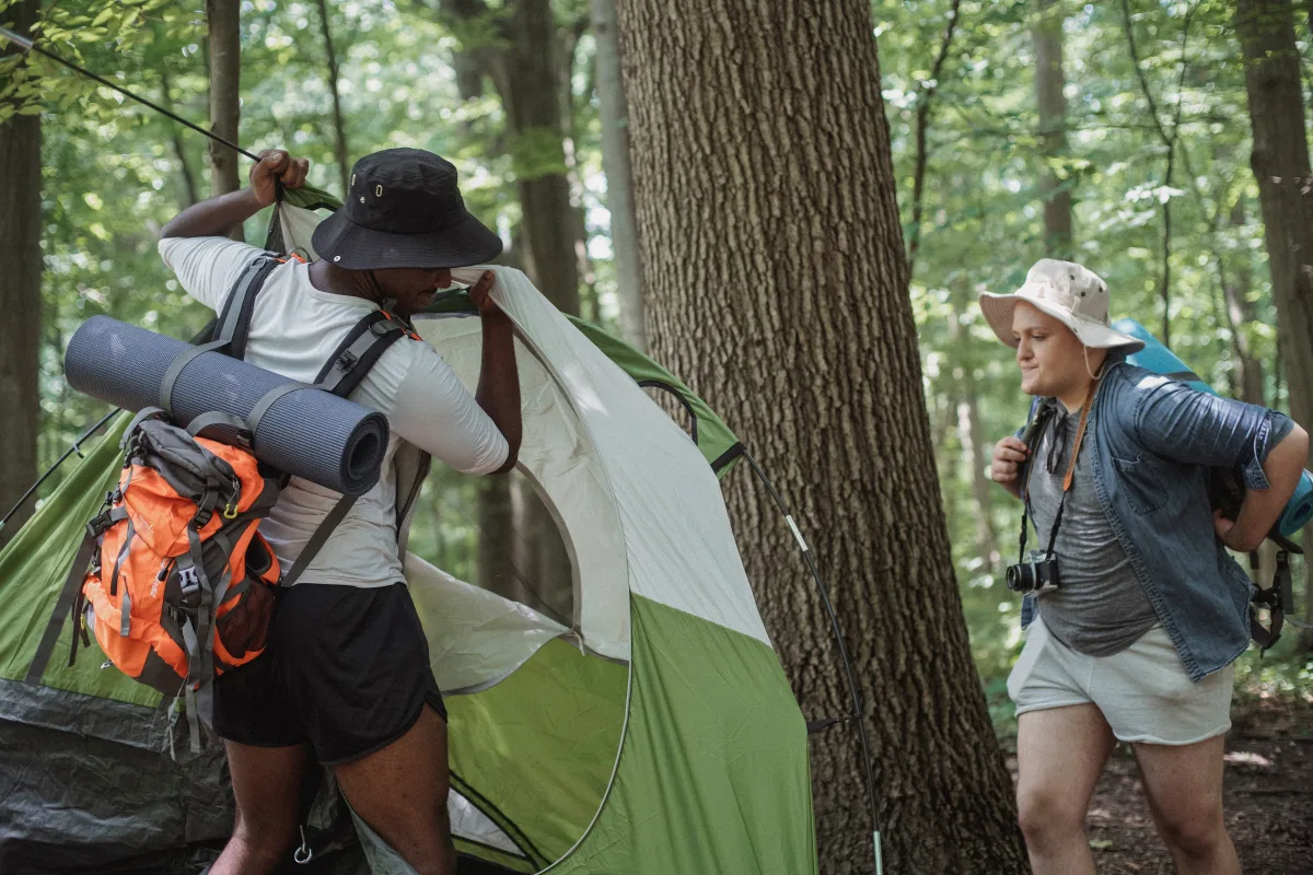 Hikers setting up a tent in a forest during a camping trip