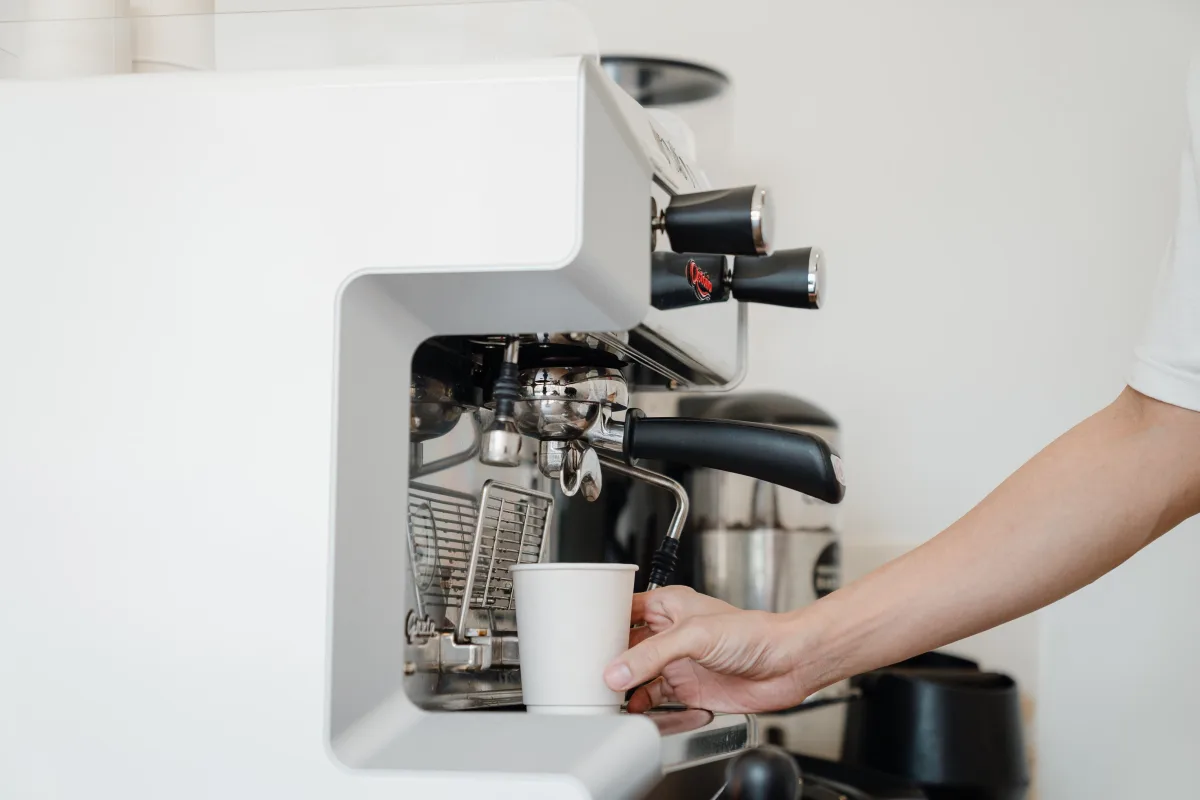 Person's hand using a drip coffee machine in a modern kitchen — best budget coffee makers under 100 dollars