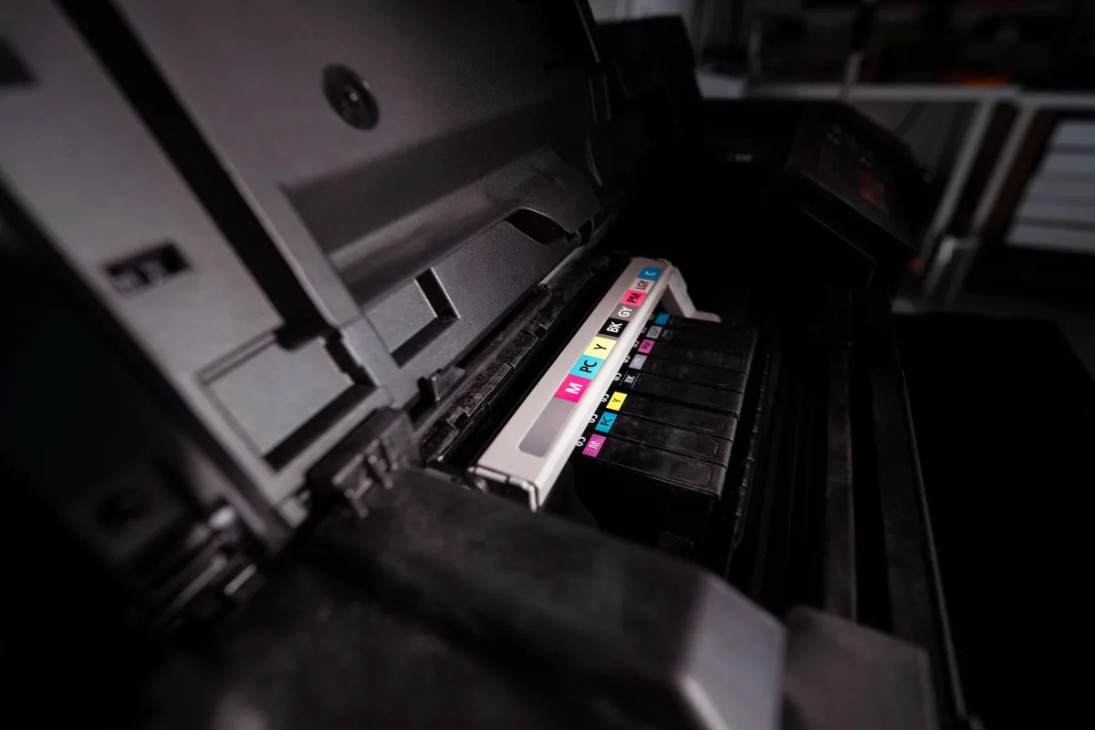 Close-up of open CMYK inkjet printer cartridges showing four color ink wells