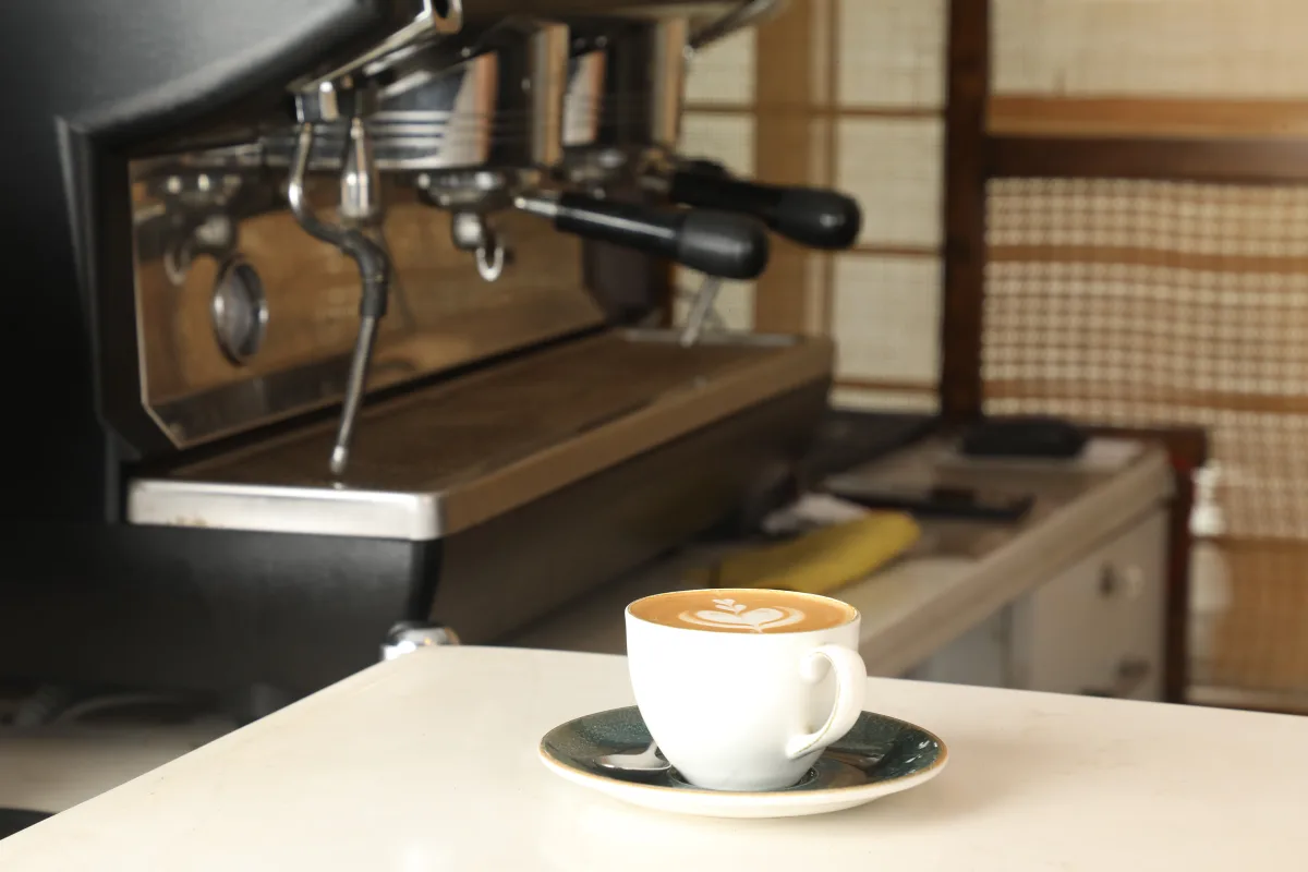 Cup of espresso with latte art in front of an elegant espresso machine — best espresso machines 2026