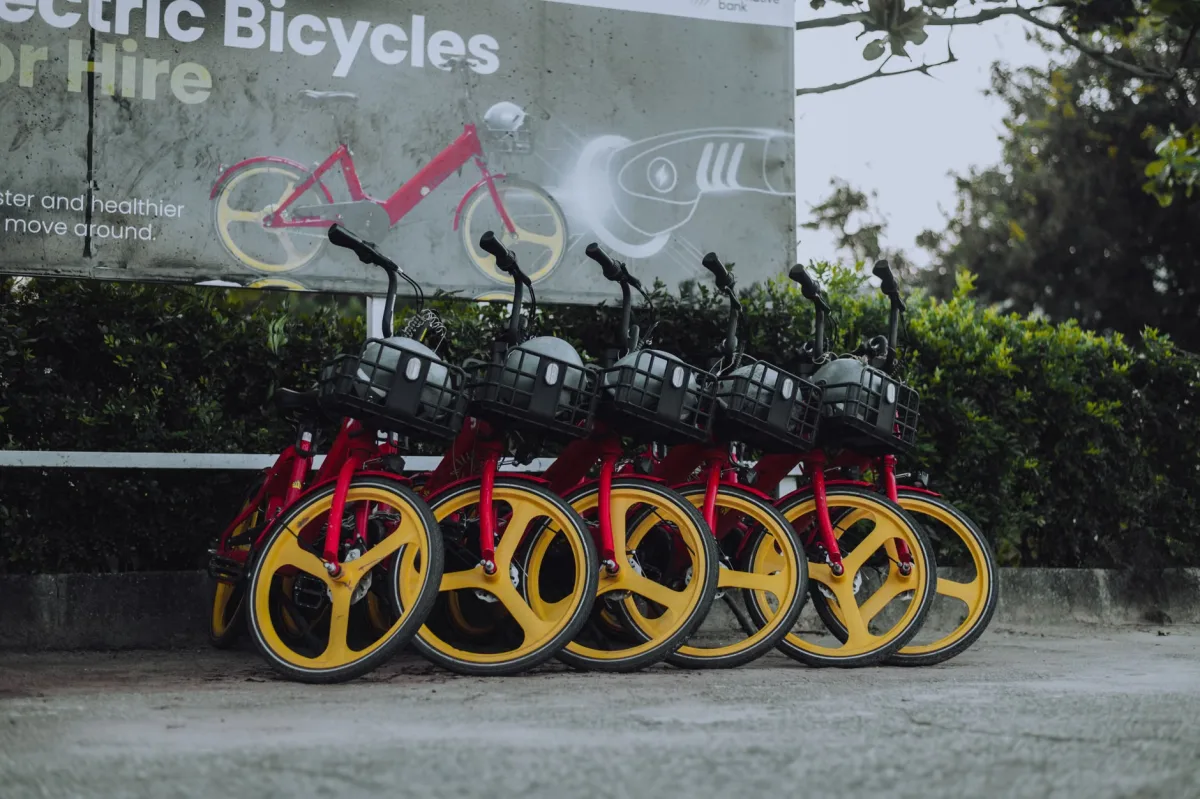 Row of red and yellow electric bikes parked on a city street, ready for riders