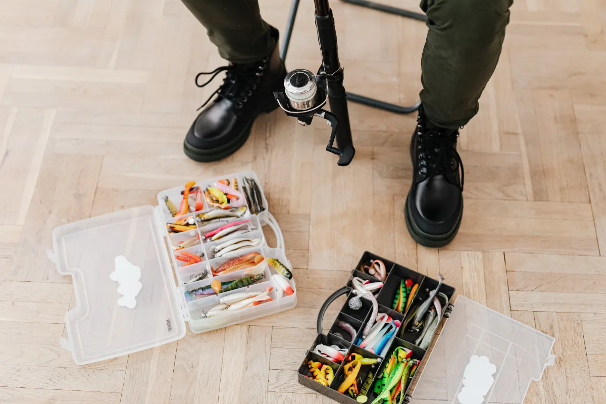 Fishing tackle boxes and wading boots on rustic wooden floor