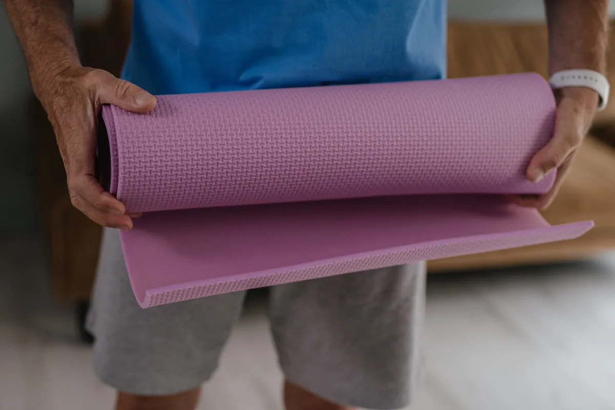 Adult man holding pink yoga mat preparing for home fitness routine