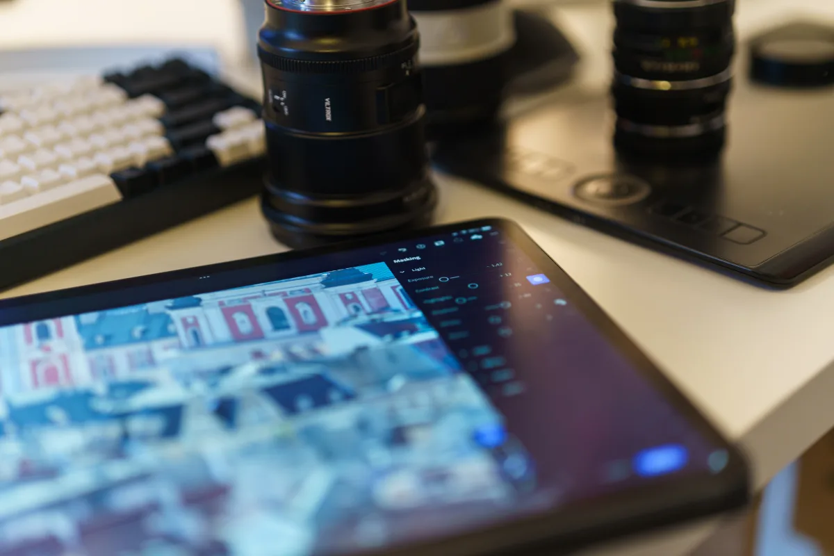 Modern photographer's workspace with tablet, camera lenses, and drawing tablet on a desk