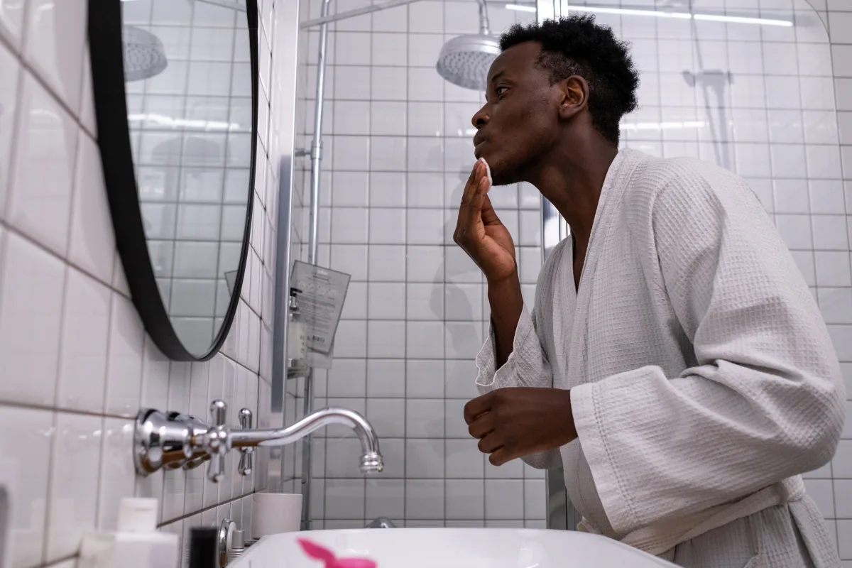 Man applying skincare routine at bathroom mirror
