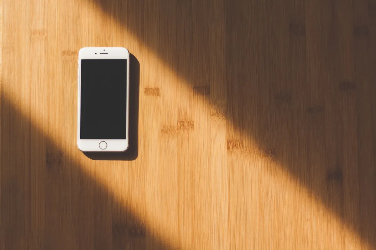 White Apple iPhone on a wooden table — Apple ecosystem for AirTag compatibility