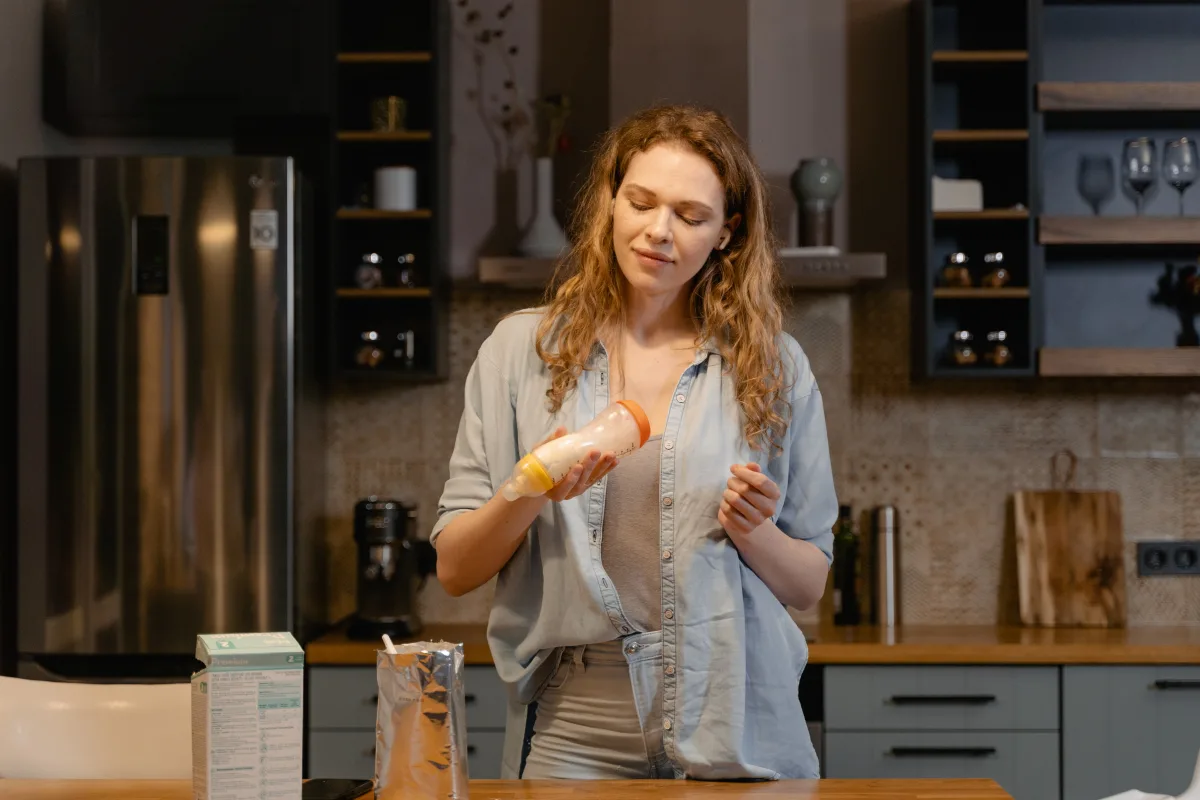 Mother carefully preparing baby bottle formula in a home kitchen