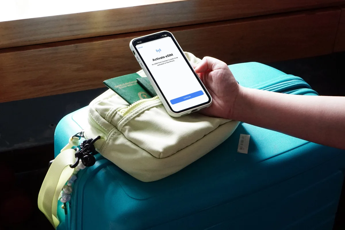 Traveler activating eSIM on smartphone over luggage
