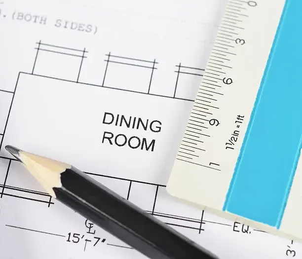 Person measuring a dining room floor to calculate table clearance