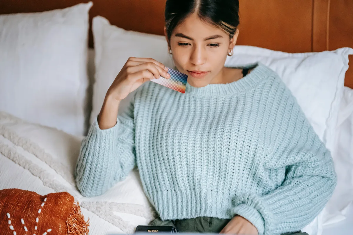 Person lying on bed with credit card, online shopping