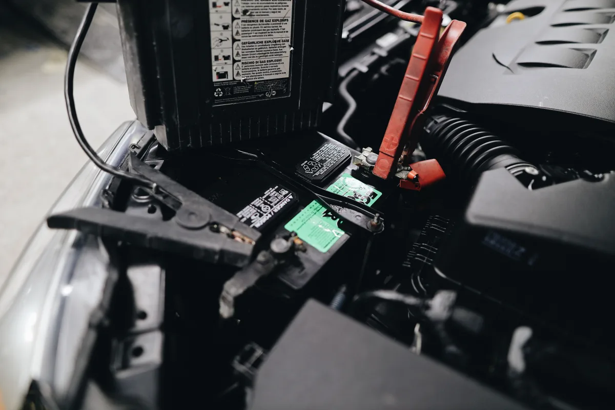 Close-up of jump starter cables attached to a car battery in engine bay