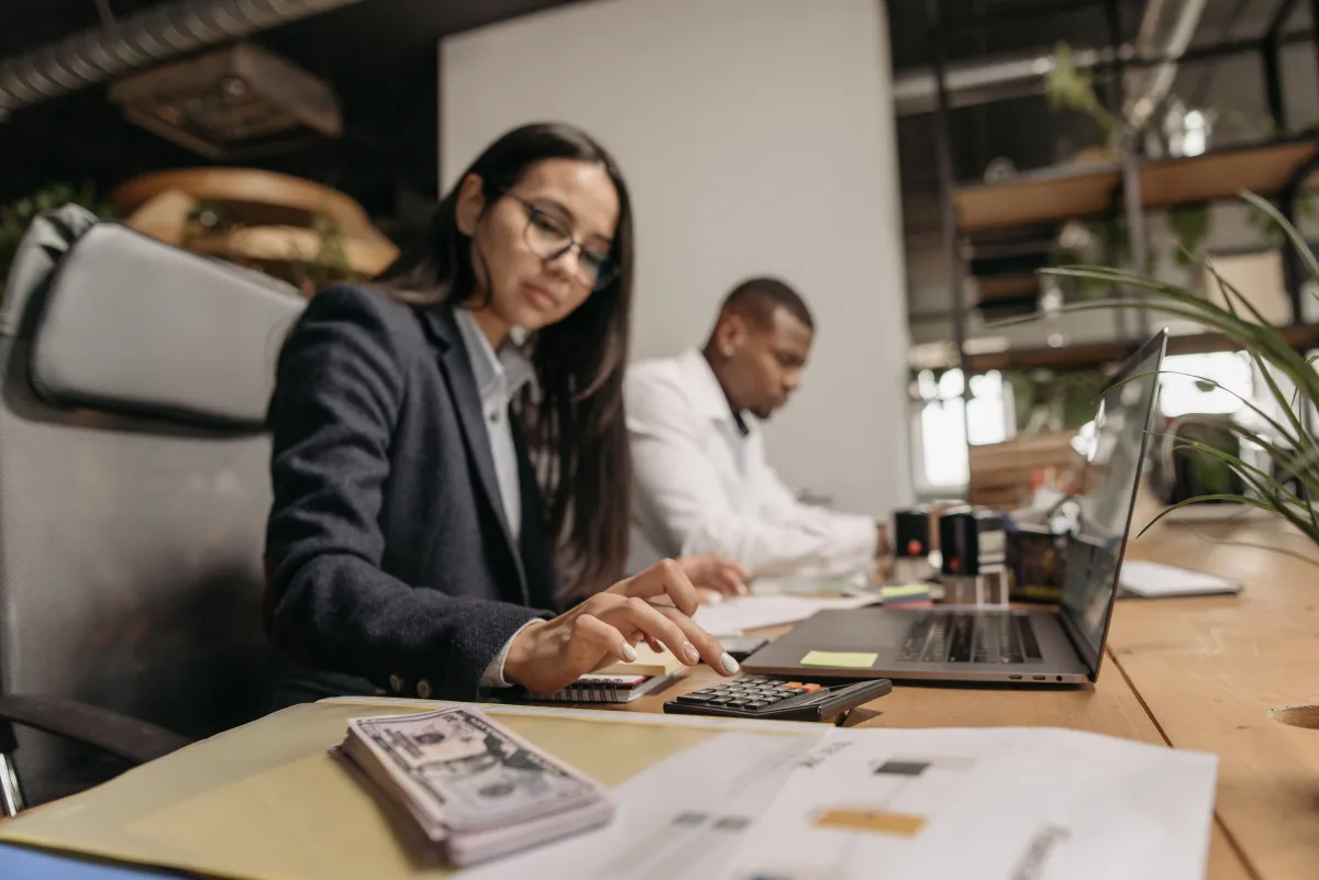 Two professionals reviewing business software options on a laptop in a modern office