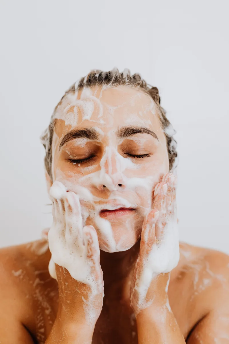 Woman washing her face with foam cleanser as the first step of a night skincare routine