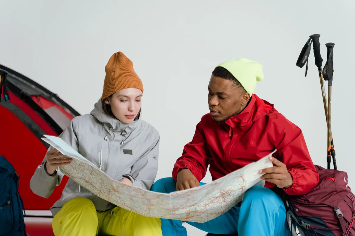 Two hikers in winter gear planning a mountain trip with a map