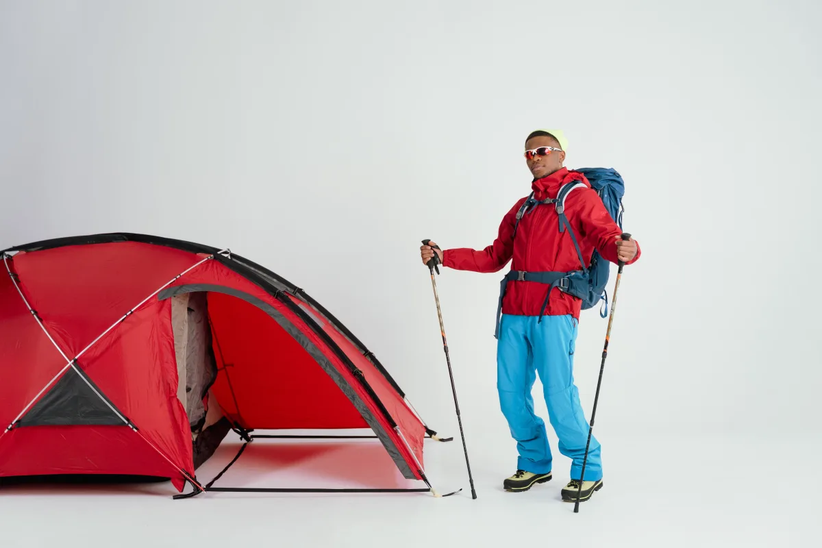 Hiker standing next to a tent in winter camping setup