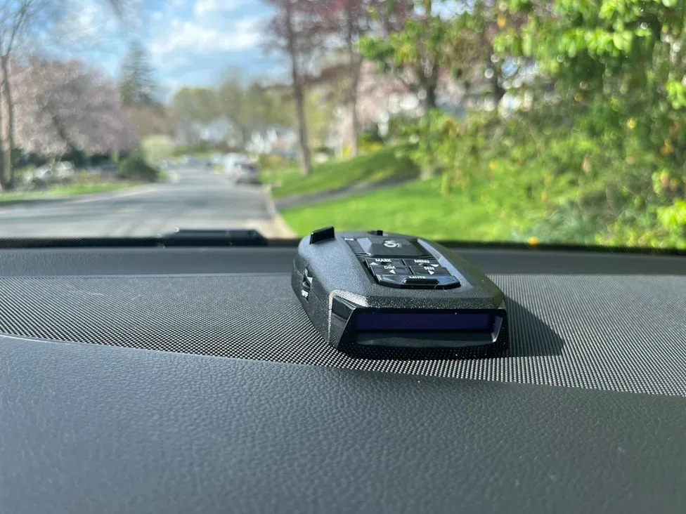 Radar detector mounted on a car dashboard showing the driver's view
