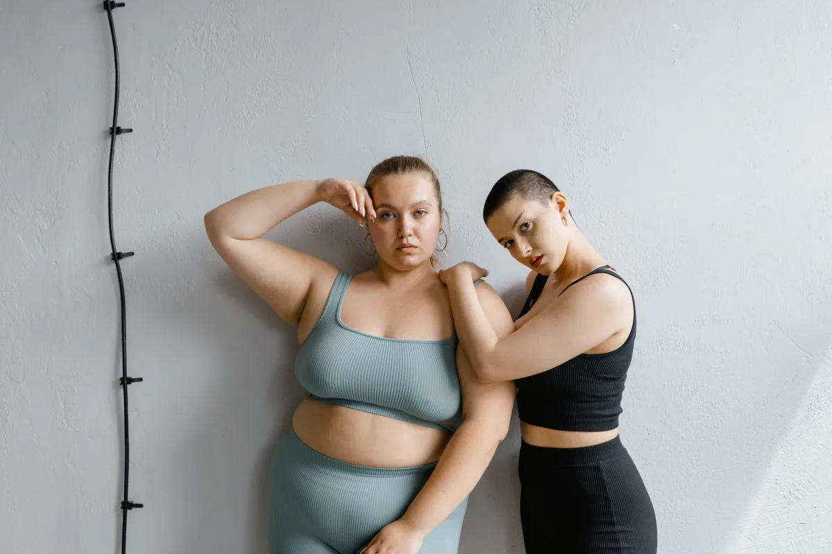 Two confident plus-size women modeling stylish outfits representing size range availability