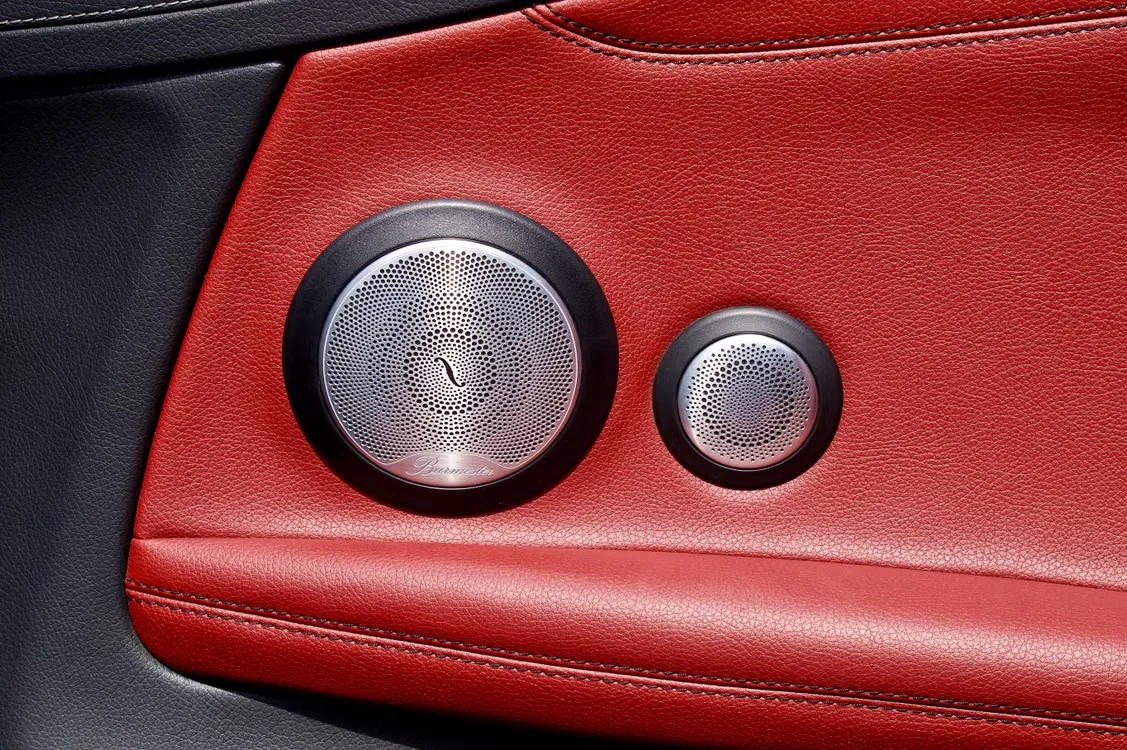 Luxury car door speaker with perforated metal grille and red leather