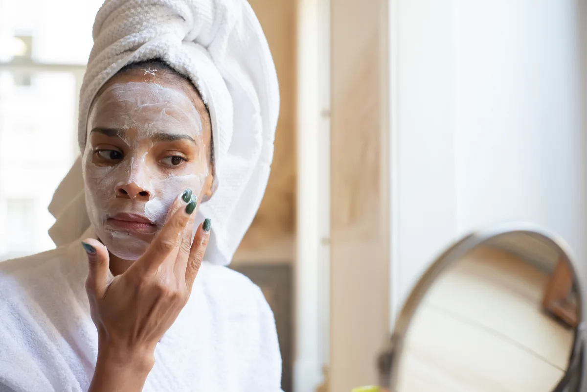 Woman applying moisturizing cream during her morning skincare routine in the bathroom