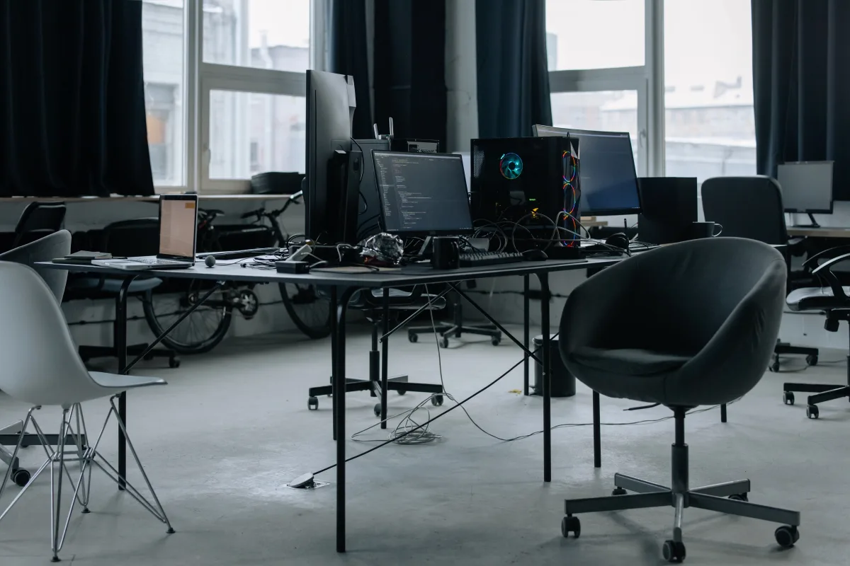 Modern office workspace with computers, ergonomic chairs, and natural light from large windows