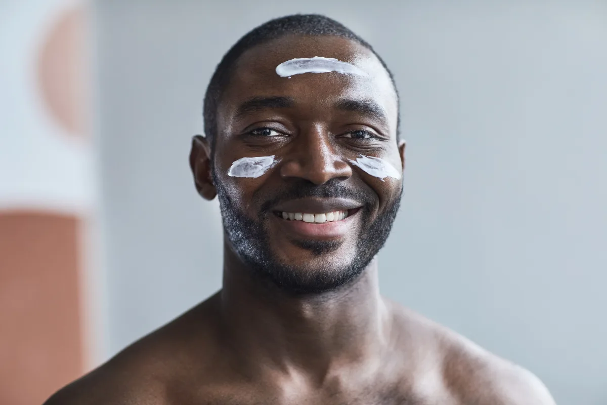 Man smiling while applying moisturizer